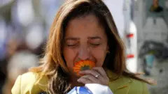 Mourner kissing an orange flower at the Bibas family funeral procession