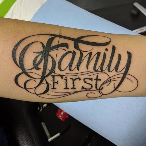 Simple &quot;Family First&quot; script tattoo on forearm, emphasizing core values.