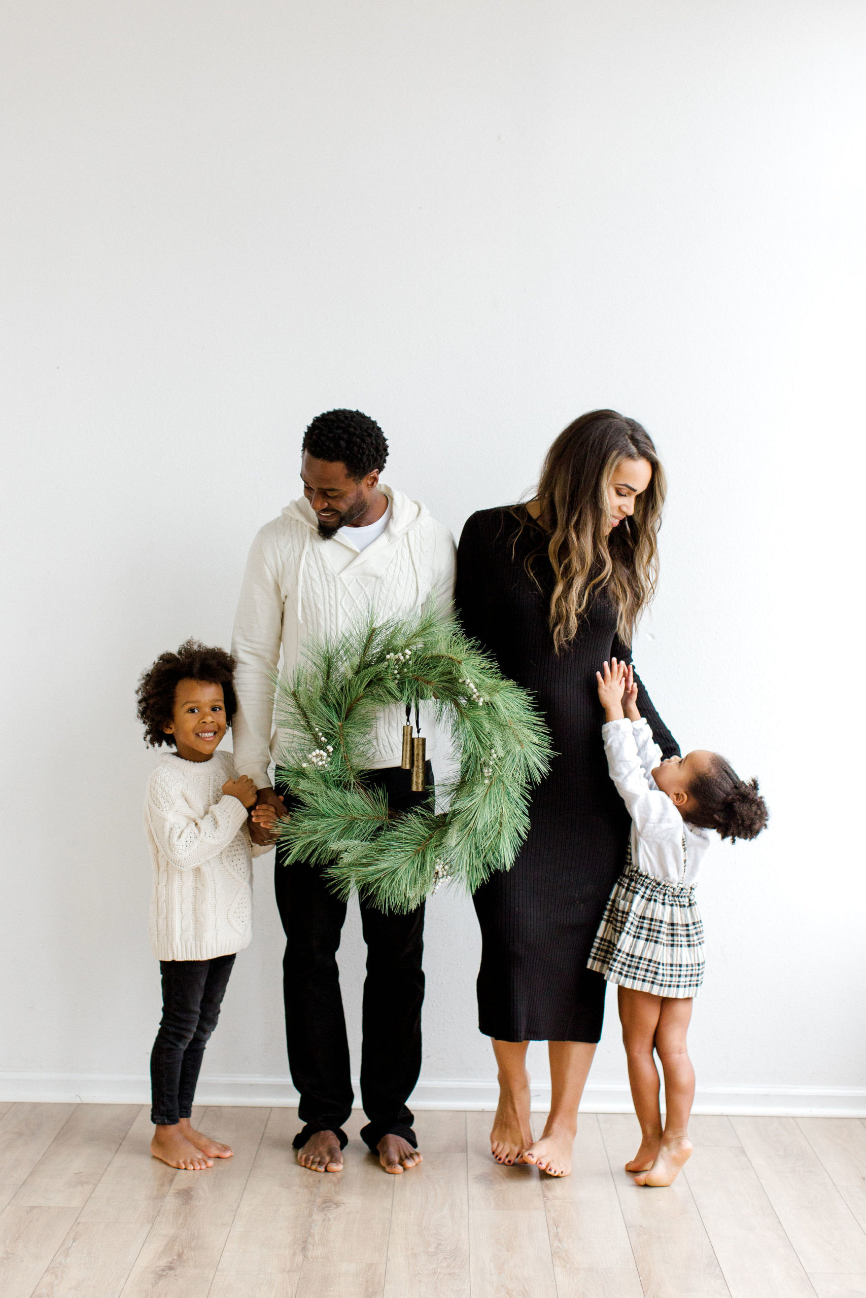 Candid family moment during a Christmas photoshoot with everyone in coordinated classic casual attire, highlighting natural interactions and relaxed style.