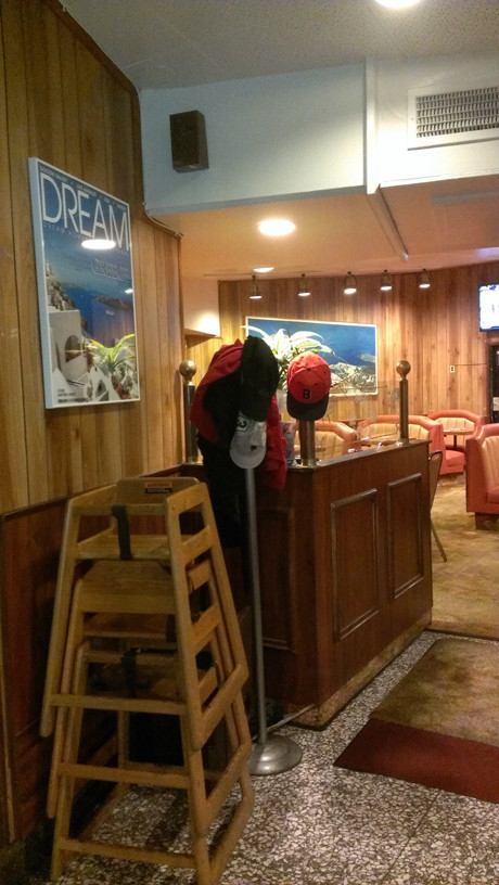 Cozy back room at Astro Family Restaurant with vintage paintings and orange booths