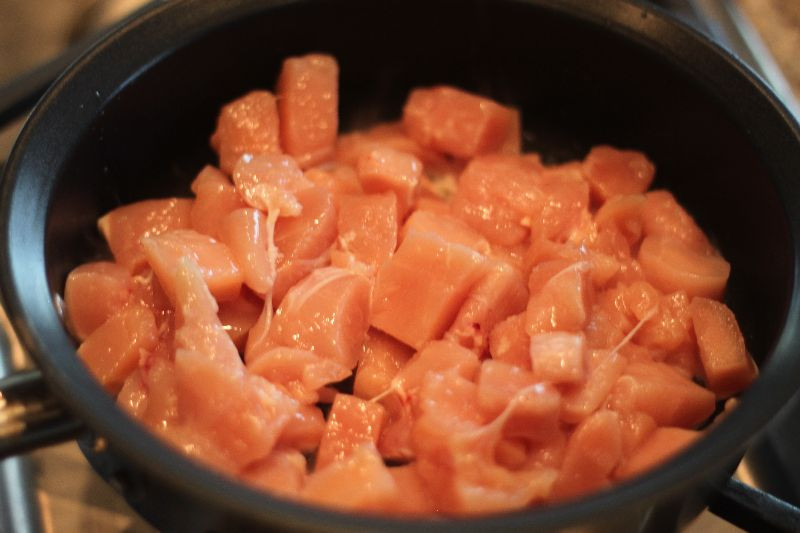 Sautéed chicken pieces in a skillet, seasoned with garlic salt, ready for the casserole.