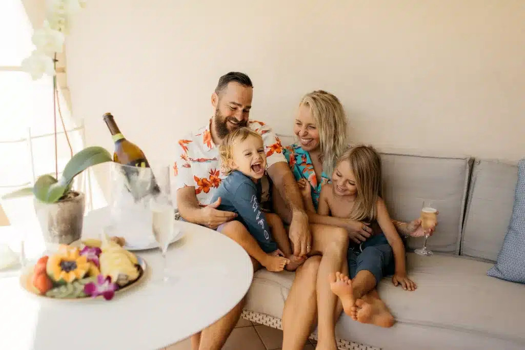 A family of four laughing and playing at the Four Seasons Resort on Oahu, Hawaii.