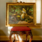 Fernando C. Amorsolo’s Fruit Market painting displayed on a chair, showcasing its vibrant colors and composition.