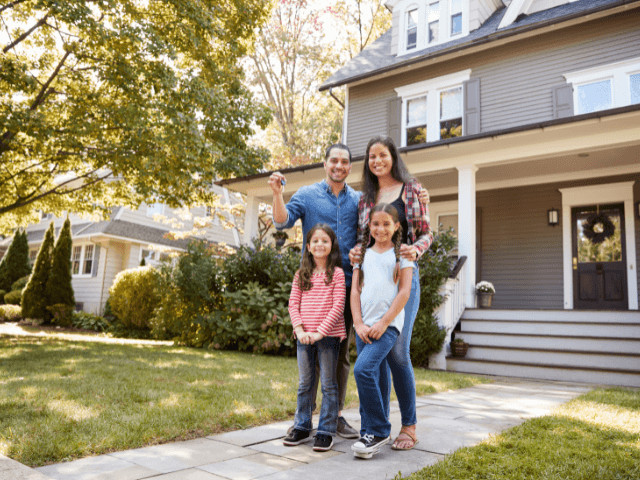 Happy family standing in front of their Winter Springs home, holding &quot;Sold&quot; sign, representing suburban family life and homeownership in Central Florida