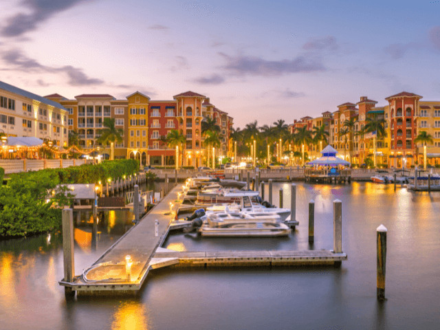 Sunset view of Naples harbor with boats and waterfront lights, portraying the city's upscale coastal charm and family-friendly evening ambiance