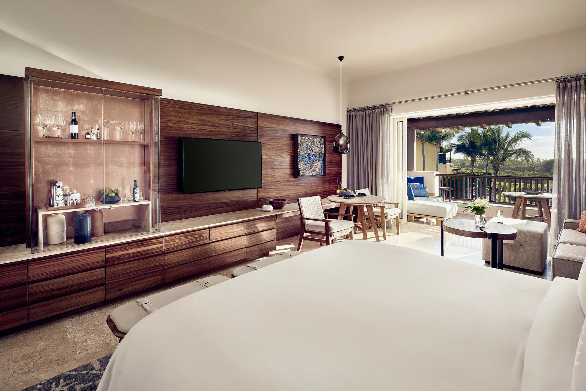 Hardwood accents and a mini bar feature prominently in a spacious hotel room with attached ocean-view balcony