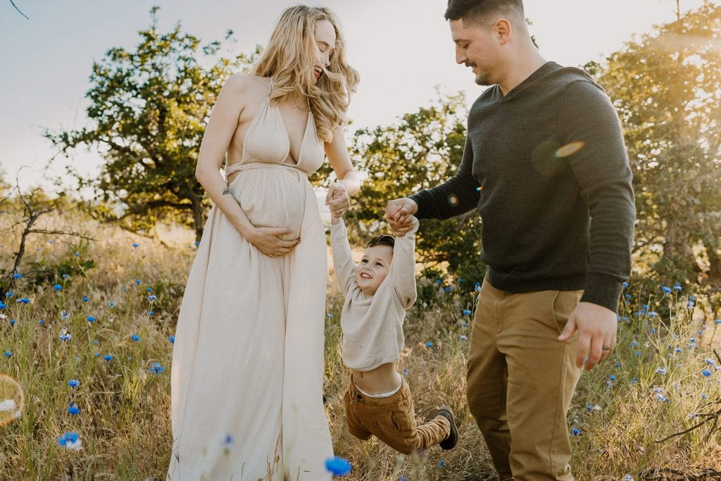 Family wearing all neutral colors swinging their little boy between them