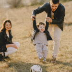 mom-and-dad-helping-her-child-play-football-family-goals