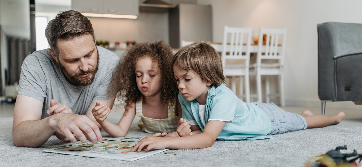 A father enjoys reading a book to his children, a son and daughter, highlighting family moments in German culture.