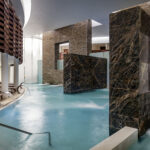 Chic pool area with marble walls and steam rising up from the water