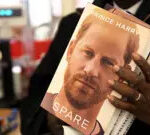 Prof Chris Imafidon holds three copies of Prince Harry's memoir, Spare, at a bookstore in London