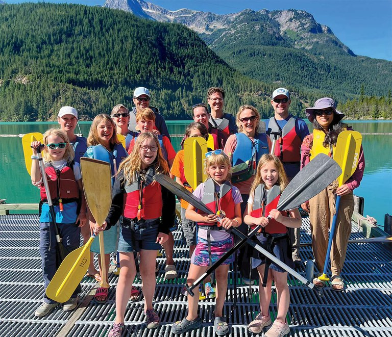 Family standing at the edge of a canyon, with vast rock formations and clear blue sky, showcasing the adventure and beauty of a family getaway.