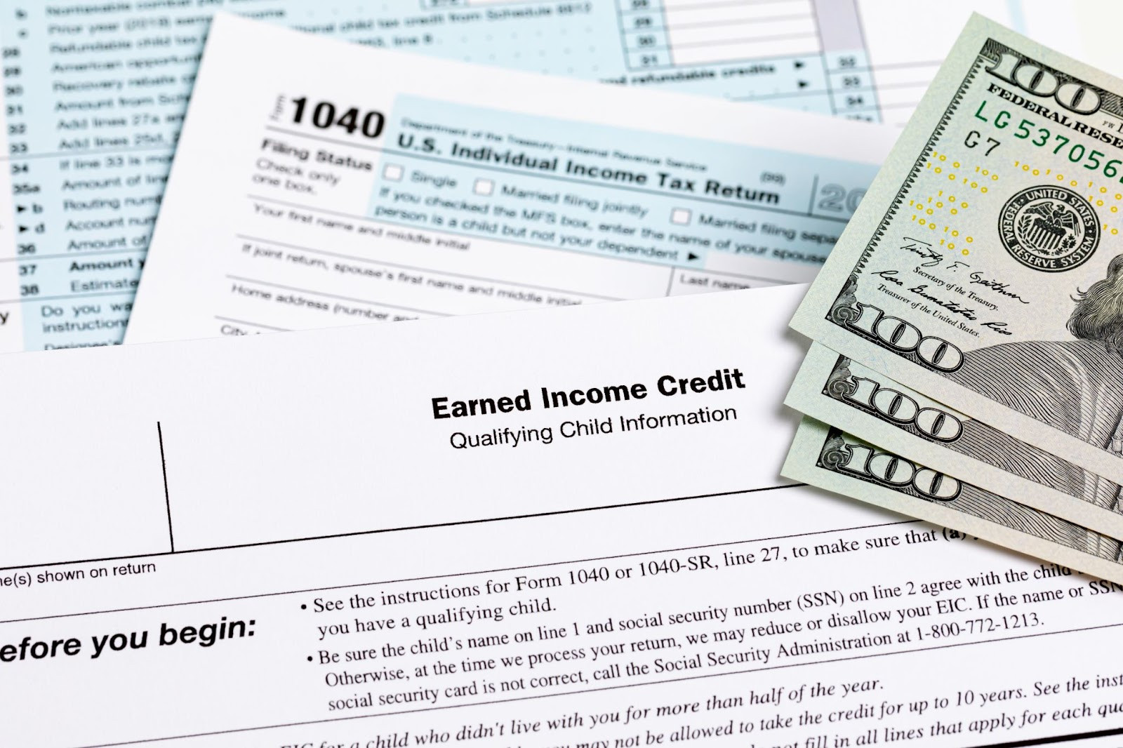 Photograph of tax forms and three 100 dollar bills