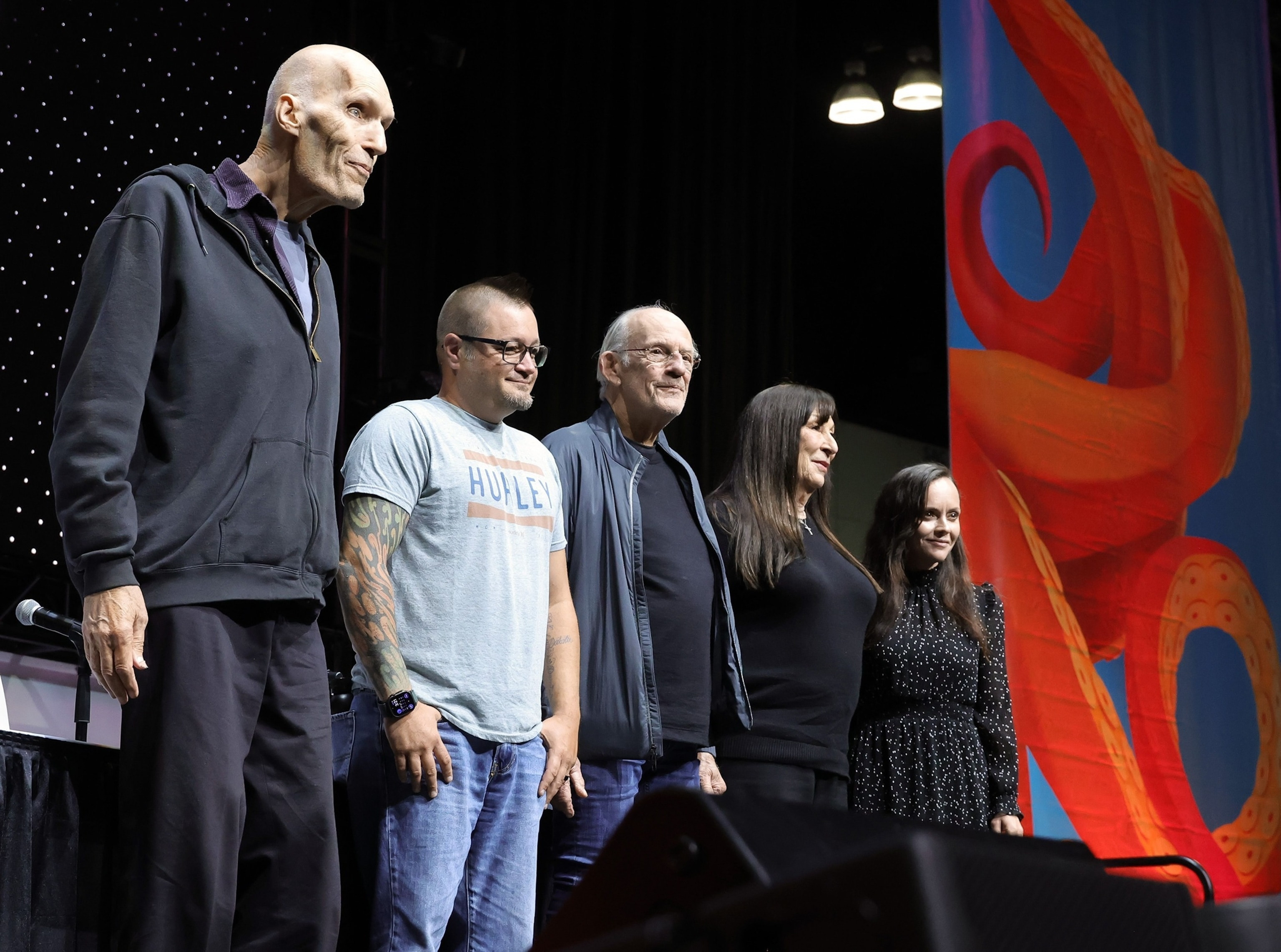 Group photo of Addams Family cast at L.A. Comic Con 2024, featuring Carel Struycken, Jimmy Workman, Christopher Lloyd, Anjelica Huston, and Christina Ricci.