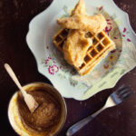 Golden crispy fried chicken and waffles served with syrup.