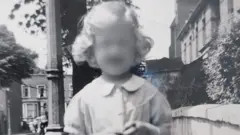Susan standing in a street with terraced housing behind her