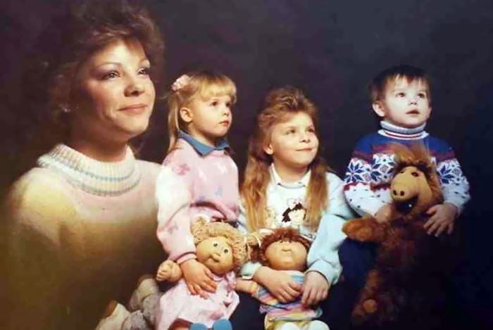 A family dressed in matching denim outfits, posing awkwardly in front of a wood-paneled wall. The alt text is: Awkward family portrait with matching denim outfits, showcasing 1980s fashion trends