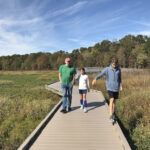 Family walking on a trail in autumn, leaves changing color, enjoying nature and family time