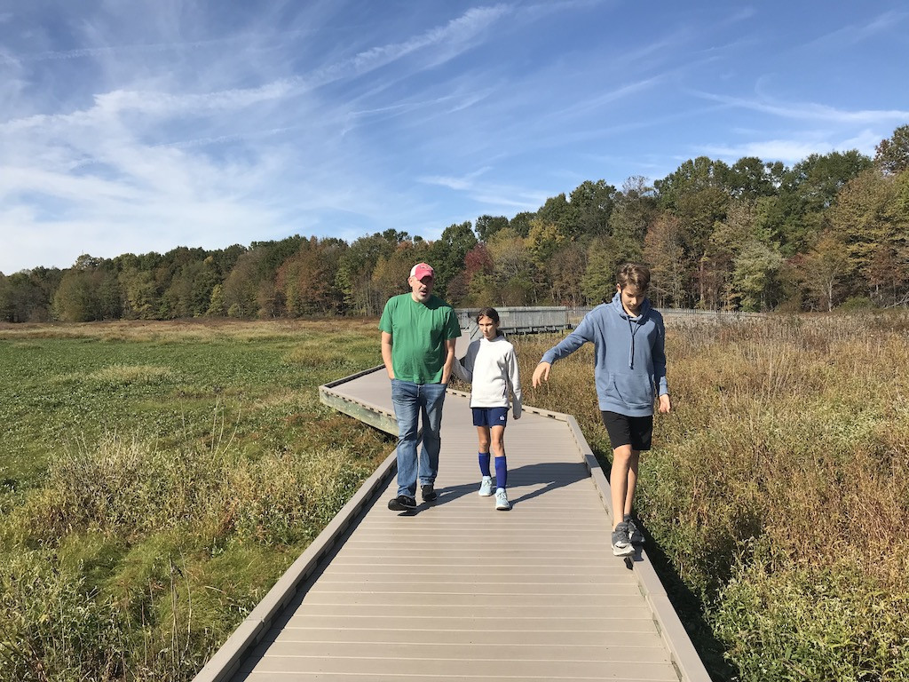 Family walking on a trail in autumn, leaves changing color, enjoying nature and family time