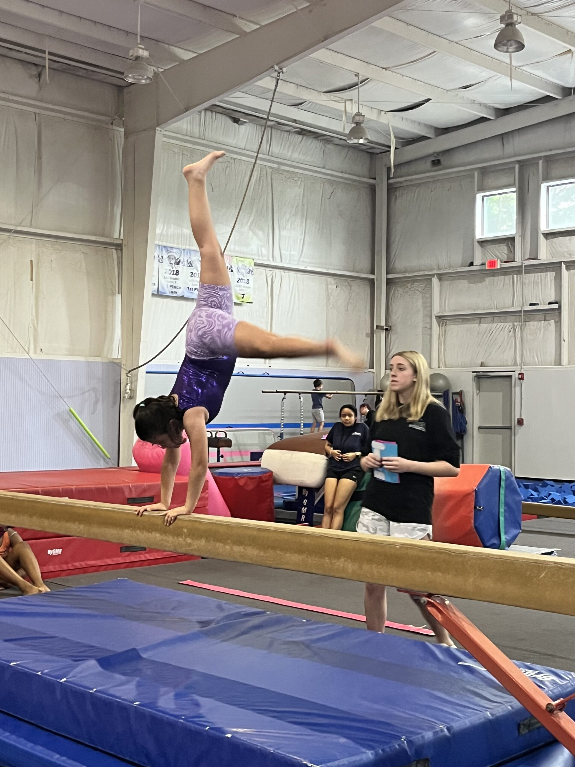 A group of children practicing on a balance beam in the Galaxy Gymnastics program at Dacula Family Sports, focusing on balance and coordination.