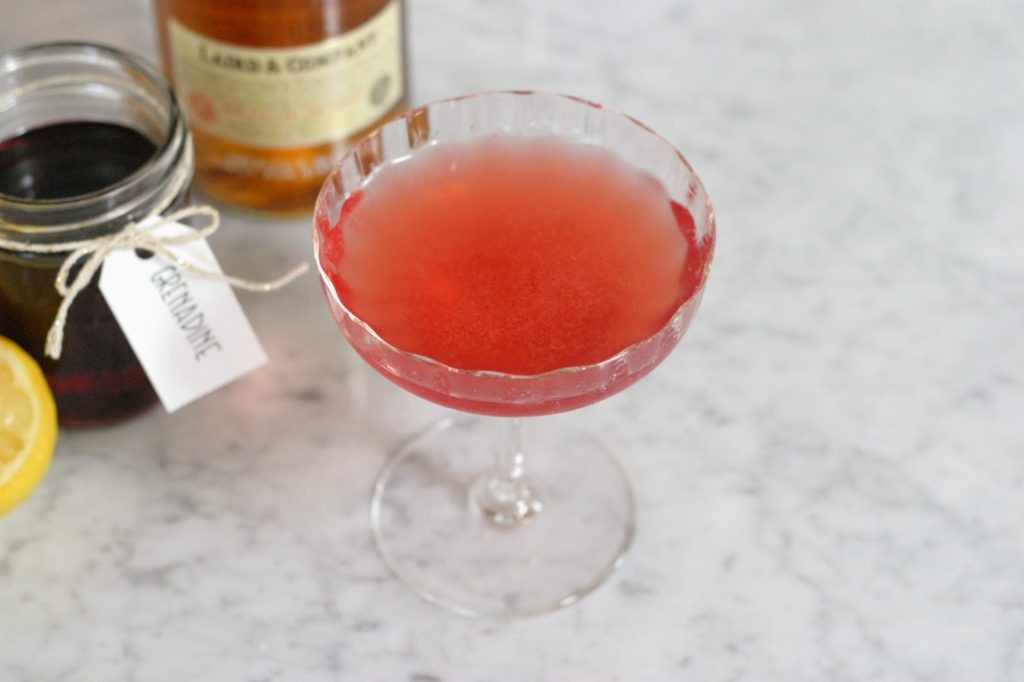 Jack Rose Cocktail Alt Text: A vibrant Jack Rose cocktail in a coupe glass, garnished with a cherry, showcasing its appealing color and presentation.